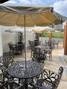 un patio al aire libre con mesas, sillas y sombrillas en Hotel Portal das Águas en Jaguariúna