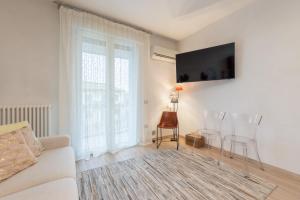 een woonkamer met een bank en een tv aan de muur bij GIOTTO Guesthouse in Due Carrare