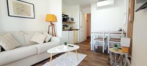 uma sala de estar com um sofá branco e uma mesa em Chez Adriana Studio VUE MER avec Piscine em Grimaud