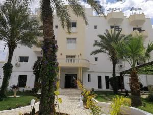 un gran edificio blanco con palmeras delante en Hotel Diar Meriam, en Sousse
