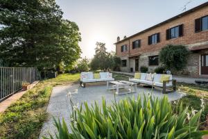 een tuin met twee banken en een tafel voor een gebouw bij Agriturismo La Collina degli Olivi in Certaldo