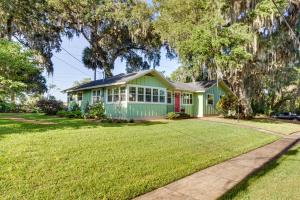 a green house with a red door on a yard at Walk to Lakes! Tropical Escape in Mount Dora in Mount Dora