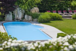 a swimming pool in a yard with chairs at Klein Fein Hotel Anderlahn in Parcines