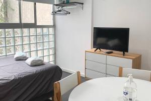 ein Schlafzimmer mit einem Bett und einem TV auf einer Kommode in der Unterkunft VLOR0404 Moderno y luminoso Studio en Belgrano in Buenos Aires