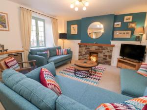 a living room with blue couches and a fireplace at Church Hill Cottage in Tavistock