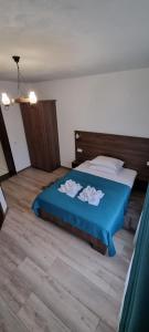 a bedroom with a blue bed with two towels on it at Popasul Moților in Răchiţele