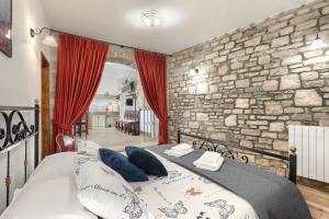 sypialnia z dużym łóżkiem i kamienną ścianą w obiekcie Apartman Pietro w mieście Motovun