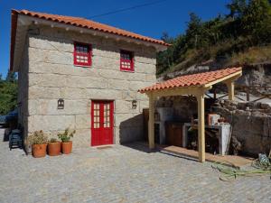 ein kleines Steinhaus mit einer roten Tür in der Unterkunft Casa antiga de pedra com piscina e vista rio in Amarante