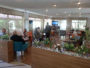 a group of people sitting at tables in a restaurant at Nazar Hotel in Didim
