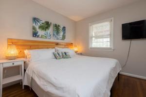 um quarto com uma cama branca e uma televisão de ecrã plano em Natural Beauty B em Virginia Beach