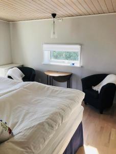 um quarto com uma cama, uma cadeira e uma janela em Blå Dörren em Torekov