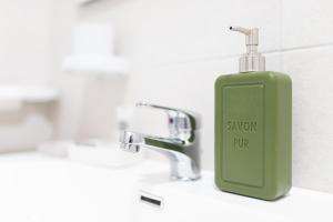 a green soap bottle sitting on a bathroom sink at areacafè affitta camere in Canicattì