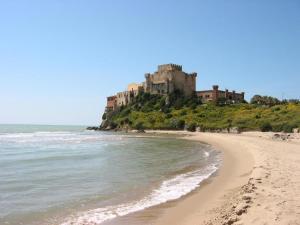 a beach with a castle on a hill next to the ocean at areacafè affitta camere in Canicattì