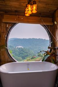 a bath tub in a room with a large window at Sky Pruek Cumulus in Mon Jam