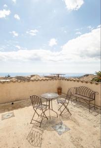 eine Terrasse mit einem Tisch, Stühlen und Meerblick in der Unterkunft Palazzo Candida B&B in Gerace