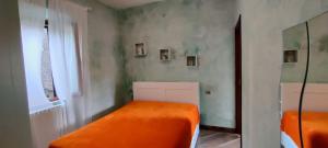 a bedroom with two beds with orange sheets at casa dei gelsi in Bolsena