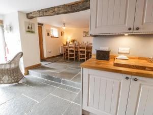 a kitchen with white cabinets and a dining room with a table at Hen Dy Craig Yr Ronwy in Bala