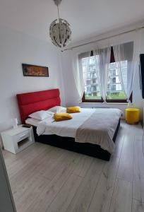 - une chambre avec un lit avec une tête de lit rouge et 2 fenêtres dans l'établissement Apartament DeLux przy Wiśle, à Cracovie