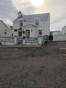 une maison blanche avec une clôture devant elle dans l'établissement Ardhill House B&B The Diamond, in the Heart of Ardara Town , F94 C7X9, à Ardara
