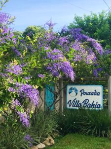 um sinal para uma villa polloda com flores roxas em Pousada Villa Bahia em Trancoso