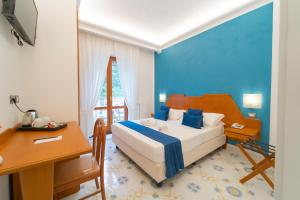 sypialnia z łóżkiem, stołem i biurkiem w obiekcie Hotel San Pietro w mieście Maiori