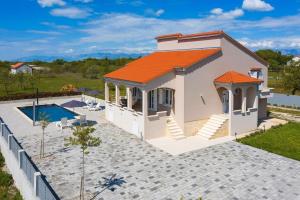 ein Haus mit einem orangenen Dach und einem Pool in der Unterkunft Ferienhaus Dalmatia bei Zadar in Zadar
