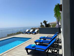 a row of blue lounge chairs next to a swimming pool at Casa Bela Vista in Venda do Atalhinho
