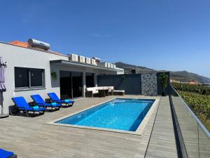 a backyard with a swimming pool and blue chairs and a house at Casa Bela Vista in Venda do Atalhinho