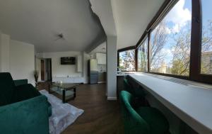 una sala de estar con muebles verdes y ventanas grandes. en Racosim Residentials, en Seleuş