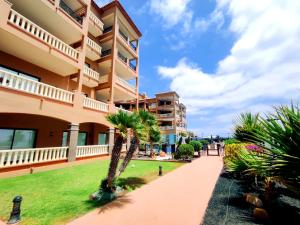 a building with a palm tree next to a sidewalk at El Nautico Suites, Golf del Sur in San Miguel de Abona