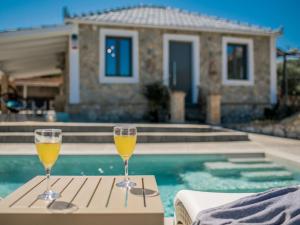 - deux verres de champagne assis sur une table à côté de la piscine dans l'établissement Binios Villa, à Vasilikos