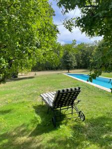a park bench sitting in the grass next to a swimming pool at LA CROIX DES GRANGES in Chapdeuil