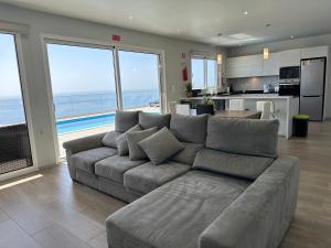 a living room with a gray couch and a kitchen at Casa Bela Vista in Venda do Atalhinho