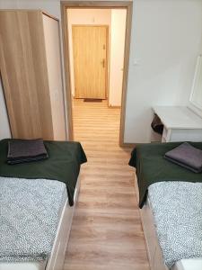 a room with two beds and a hallway with a door at Apartament Green Hill in Szklarska Poręba