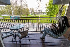 a young child sitting in a hammock on a porch at Tisza Gyöngye Apartmanok in Szeged