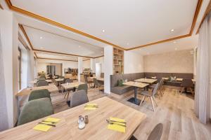 ein Restaurant mit Holztischen und -stühlen sowie einem Tisch in der Unterkunft Hotel Garni Gästehaus am Mühlbach in Ottobeuren