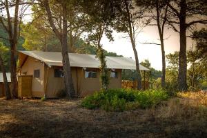 una casa amarilla con una tienda en el bosque en Glamping VALL de CODÓ en Terrades