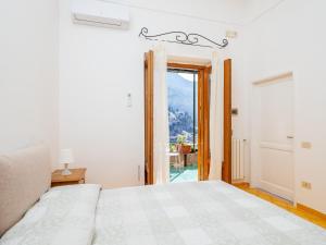 Dormitorio blanco con cama y puerta corredera de cristal en Rosa House - Breathtaking View of the Amalfi Coast, en Positano