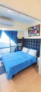 a large blue bed in a room with a window at Aveline Suites Executive City View ACQUA Private Residences near Rockwell Makati in Manila