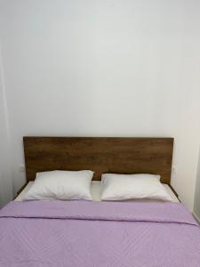 a bed with a wooden headboard and two white pillows at Maria Galini Home in Agia Galini