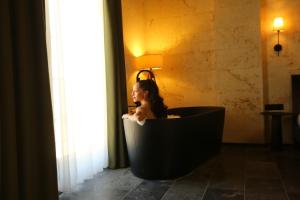 uma mulher sentada numa banheira preta numa sala em Perla Cappadocia em Goreme