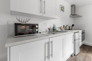 a white kitchen with a microwave and a sink at Exeter City Centre Apartments Ashton Apartment in Exeter