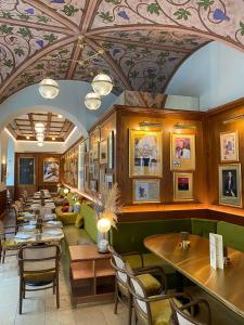 ストラスブールにあるMaison Kammerzell - Hotel & Restaurantのテーブルと椅子、絵画が飾られた天井のレストラン