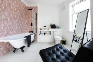 a bathroom with a tub and a black leather chair at Neighbourhood Bedrooms in Cardiff