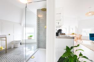 a bathroom with a glass shower and a kitchen at Neighbourhood Bedrooms in Cardiff