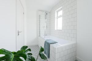 a white bathroom with a tub and a window at Neighbourhood Bedrooms in Cardiff