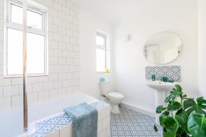 a bathroom with a tub and a toilet and a mirror at Neighbourhood Bedrooms in Cardiff
