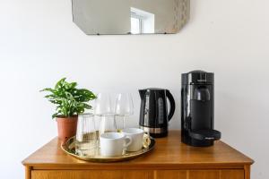 a coffee maker and cups on a wooden table at Neighbourhood Bedrooms in Cardiff