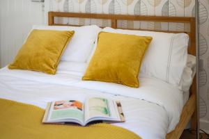 a book laying on a bed with yellow pillows at Neighbourhood Bedrooms in Cardiff