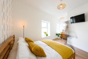 a bedroom with a bed with yellow pillows at Neighbourhood Bedrooms in Cardiff